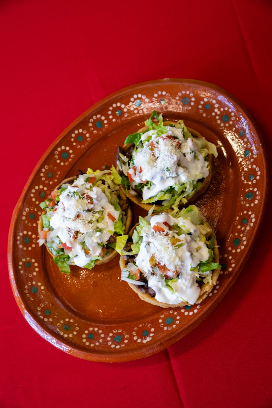 Sopes topped with lettuce, crema and cotija